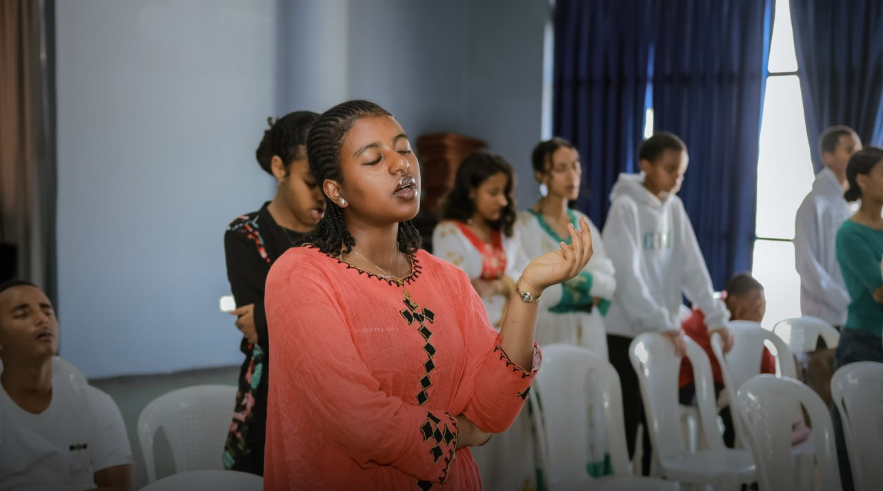 A student worshipping with her eyes closed