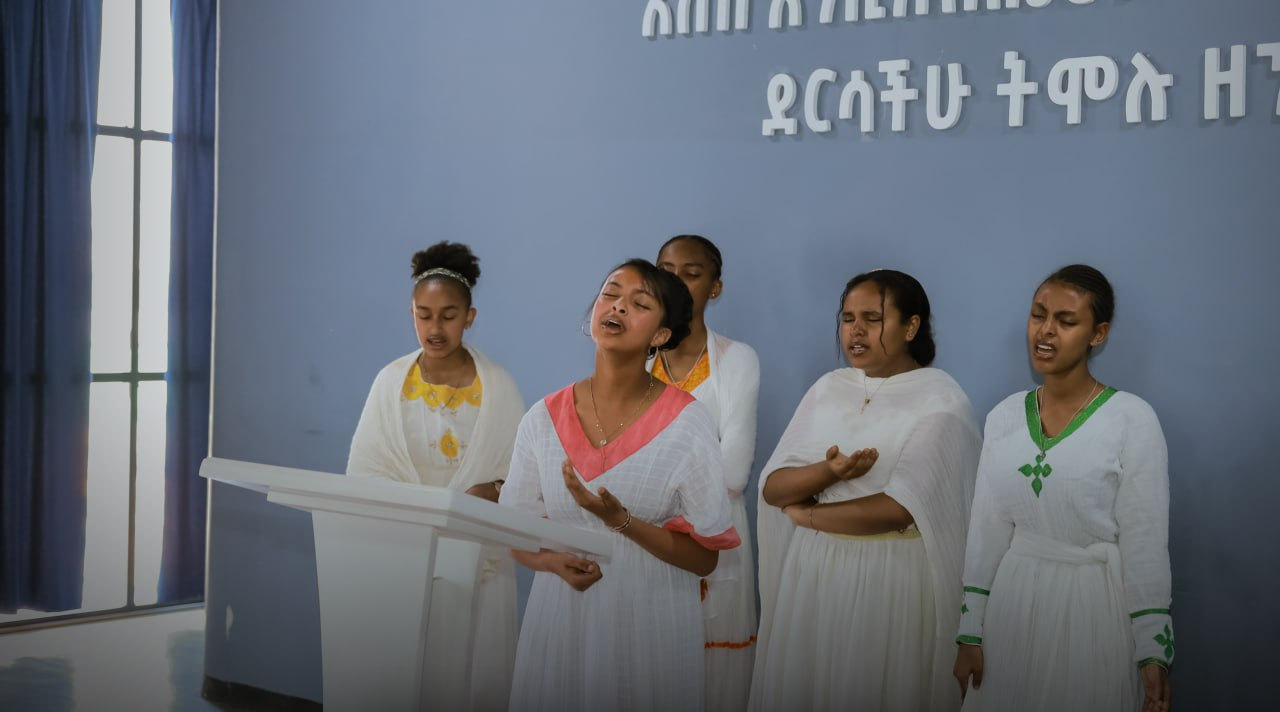 Students in traditional dress singing on stage