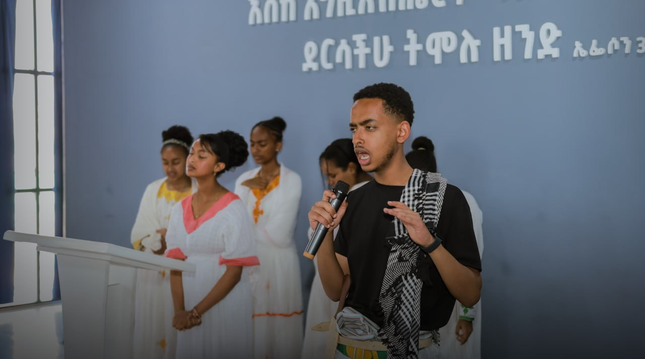 A speaker with a microphone beside singers